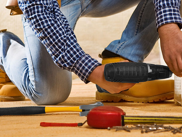 Contractor kneeling on floor using drill
