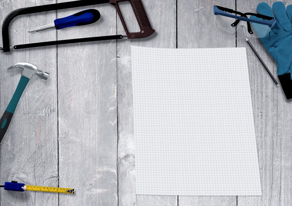 Blank piece of white graph paper surrounded by construction tools