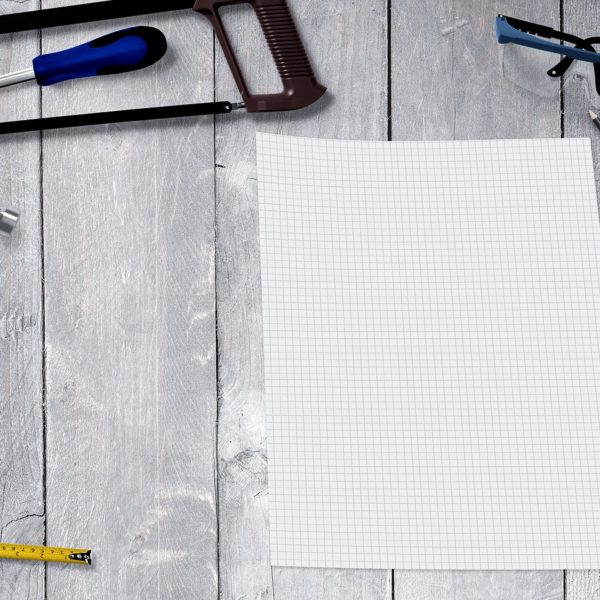 Blank piece of white graph paper surrounded by construction tools