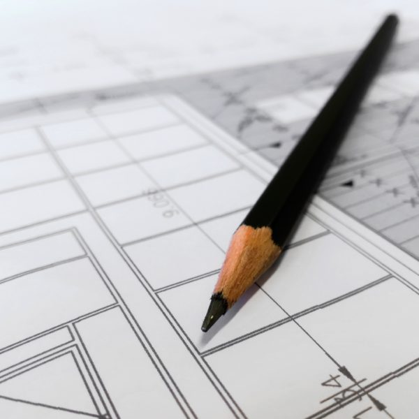 close-up view of a sharpened pencil laying on architecture plans