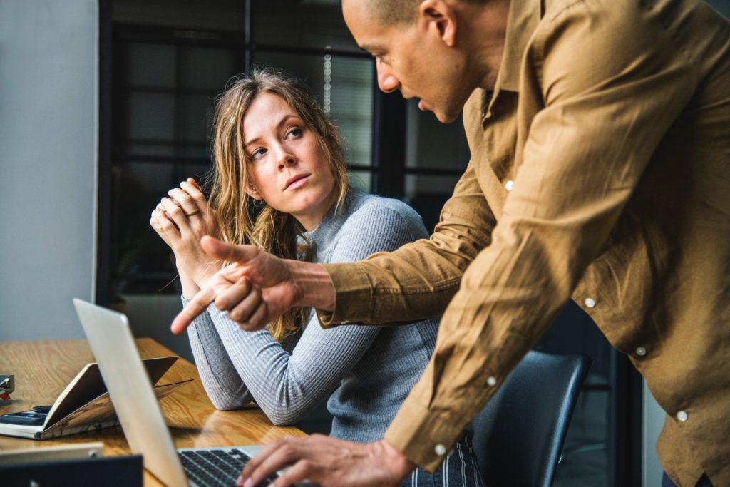 Woman with ponytail talking with guy pointing at computer