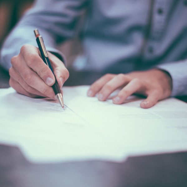 Man in collared business shirt signing contract