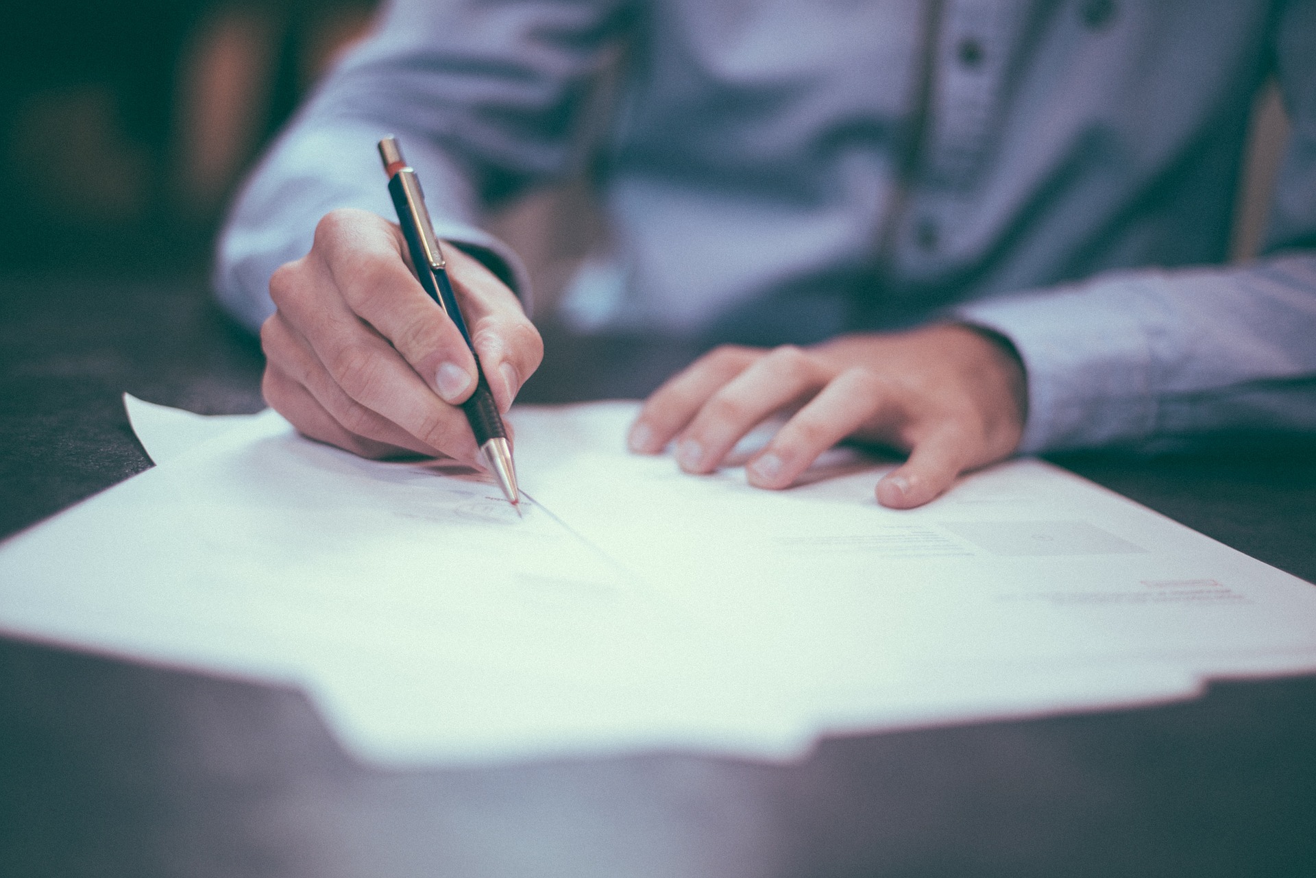 Man in collared business shirt signing contract