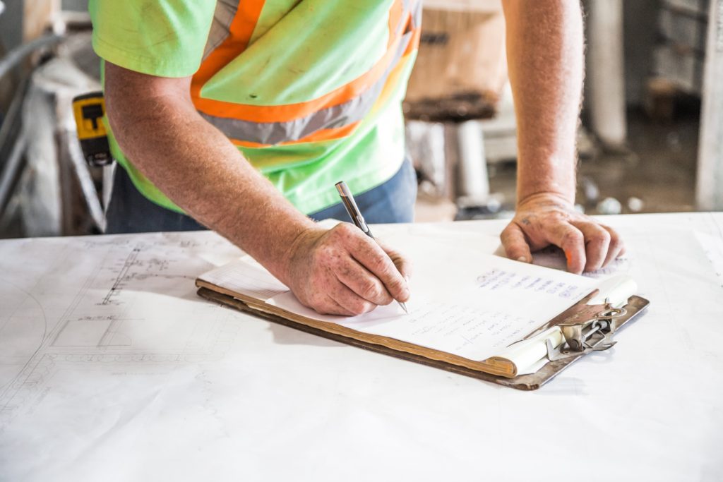 Construction worker writing on clipboard