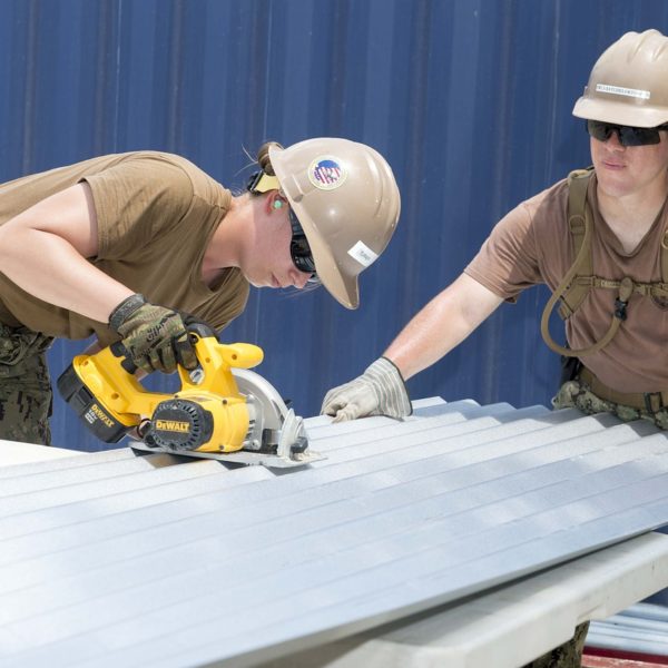 Two military contractors cutting corrugated steel sheet