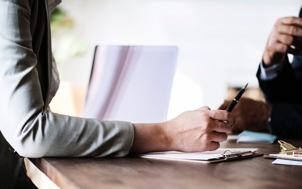 person at table holding pen and looking through papers with contractor