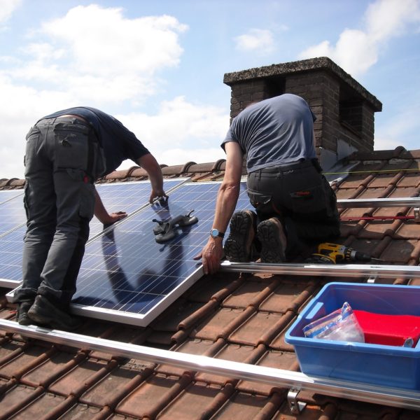 two men installing solar panels on roof of commercial property