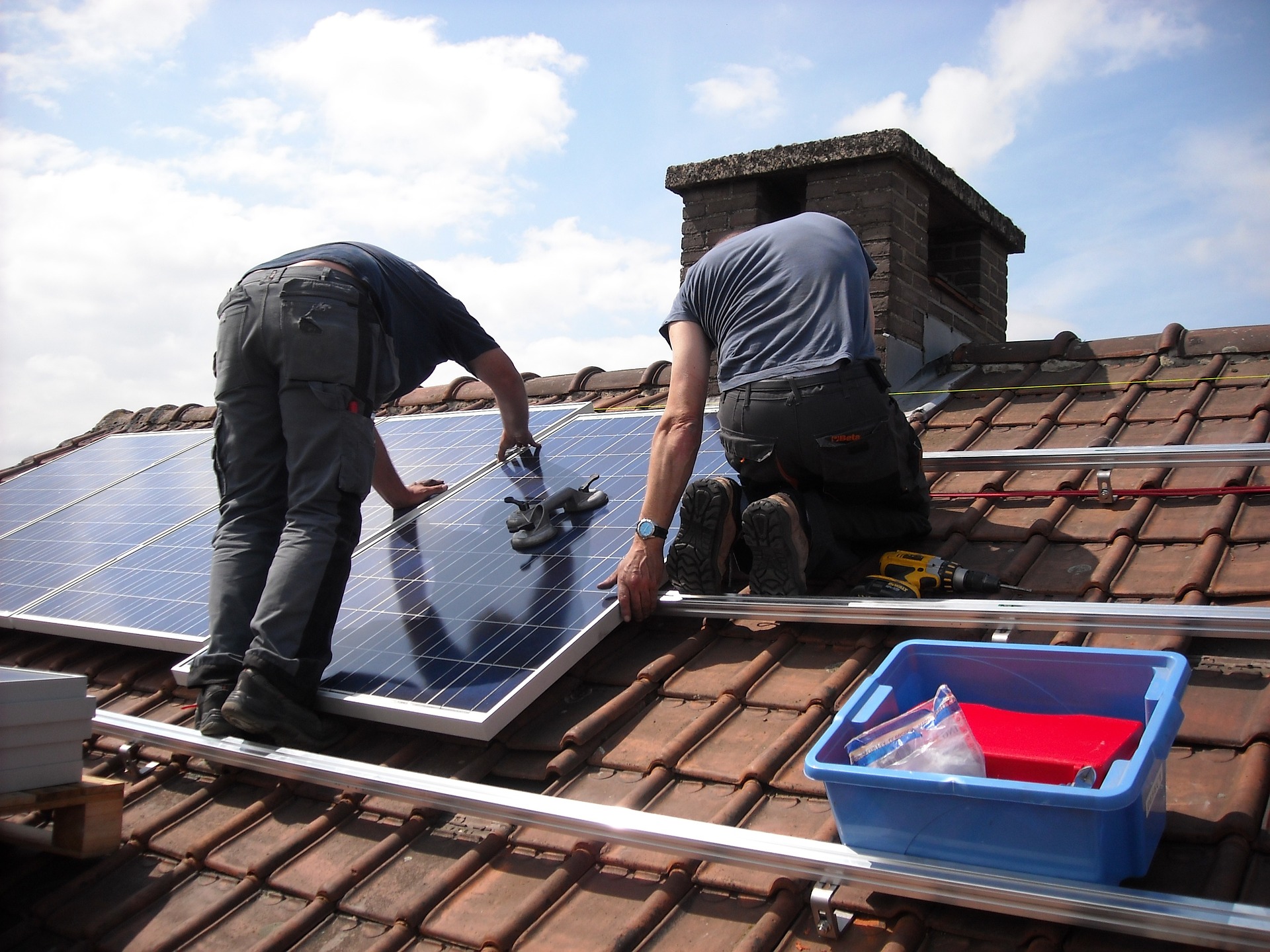 two men installing solar panels on roof of commercial property
