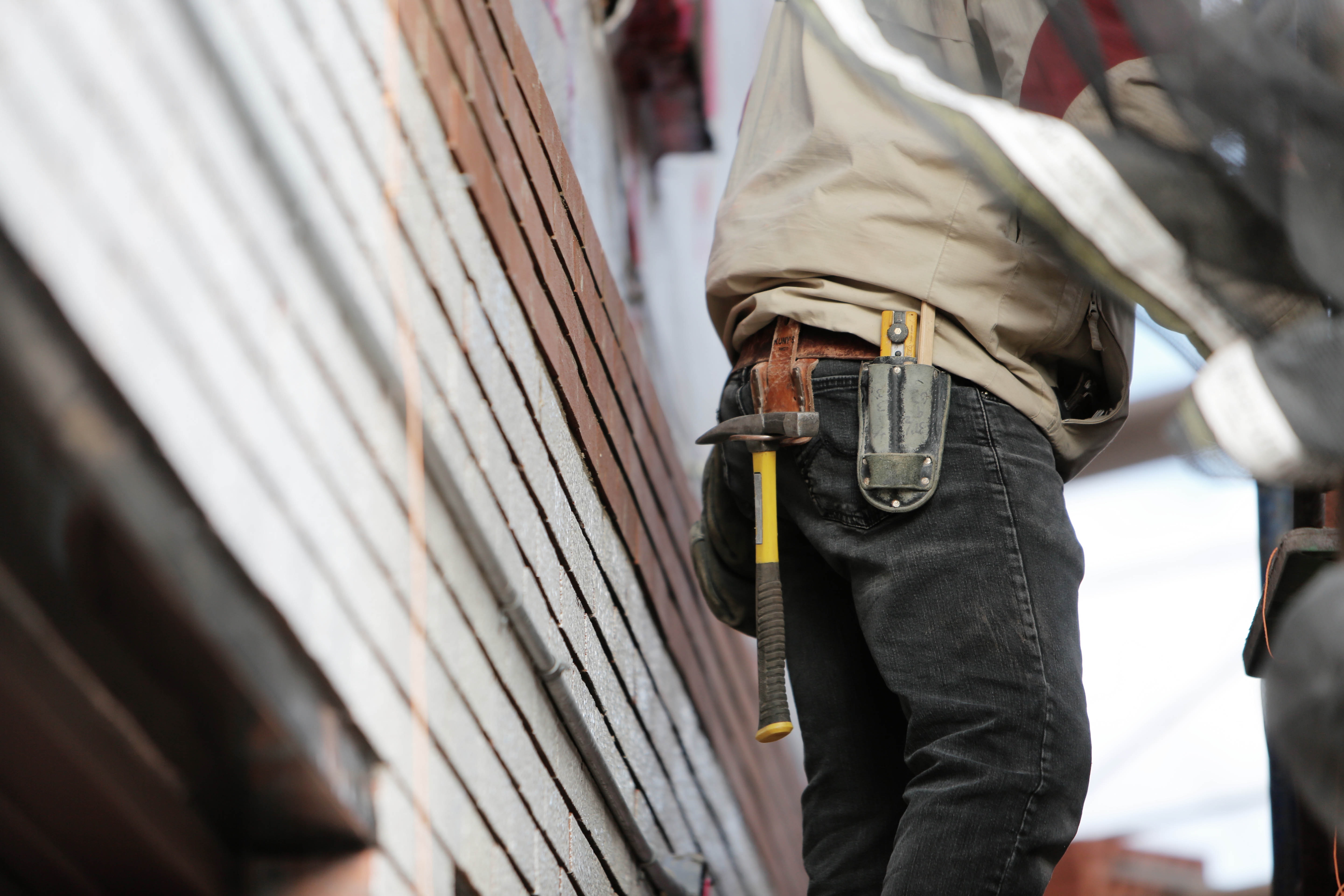 handyman with toolbelt next to damaged building