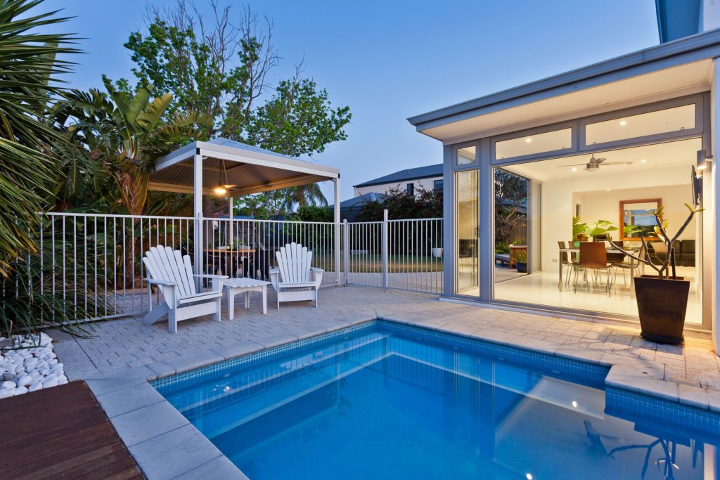 outdoor pool and two white adirondack chairs