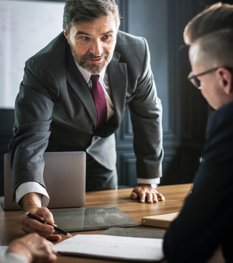 businessman uses his pen to point out important notes to two potential clients