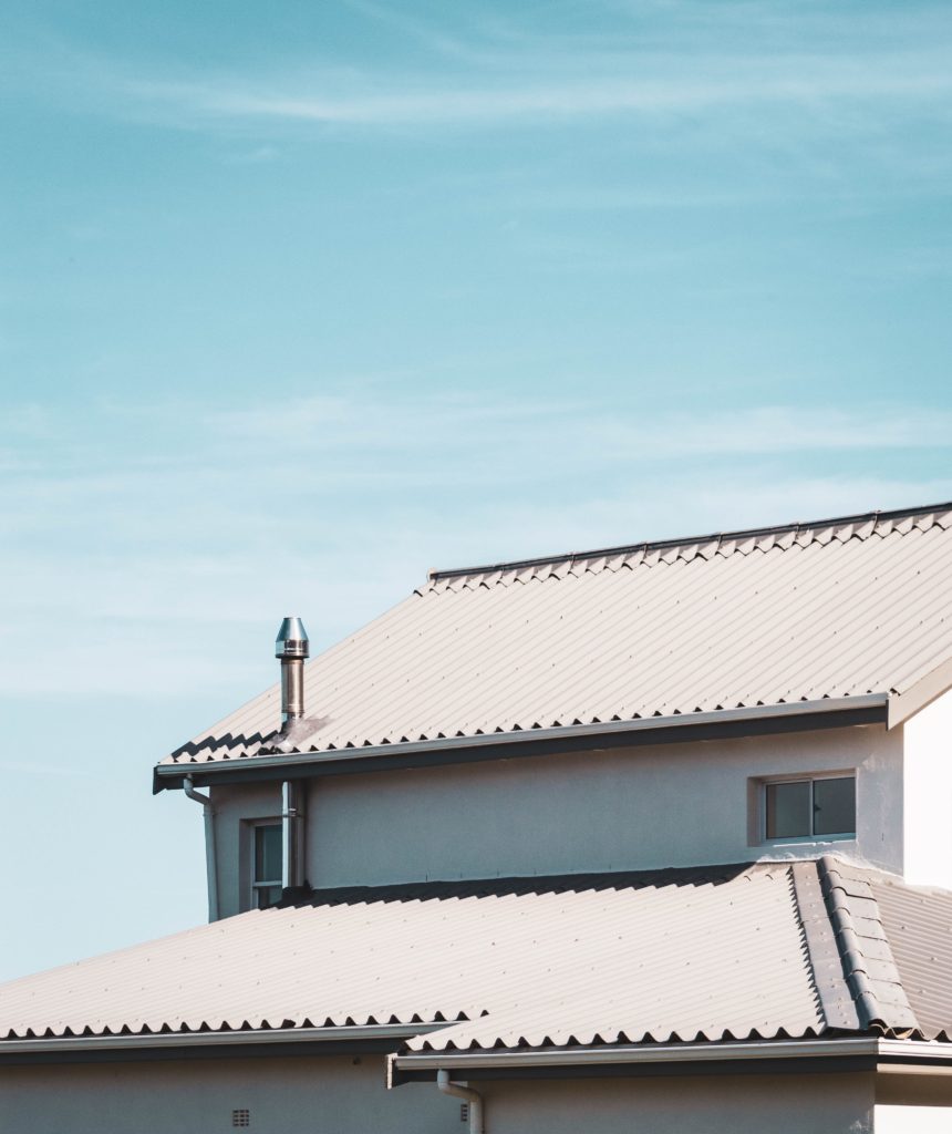 white stucco house with gray steel roof against blue sky