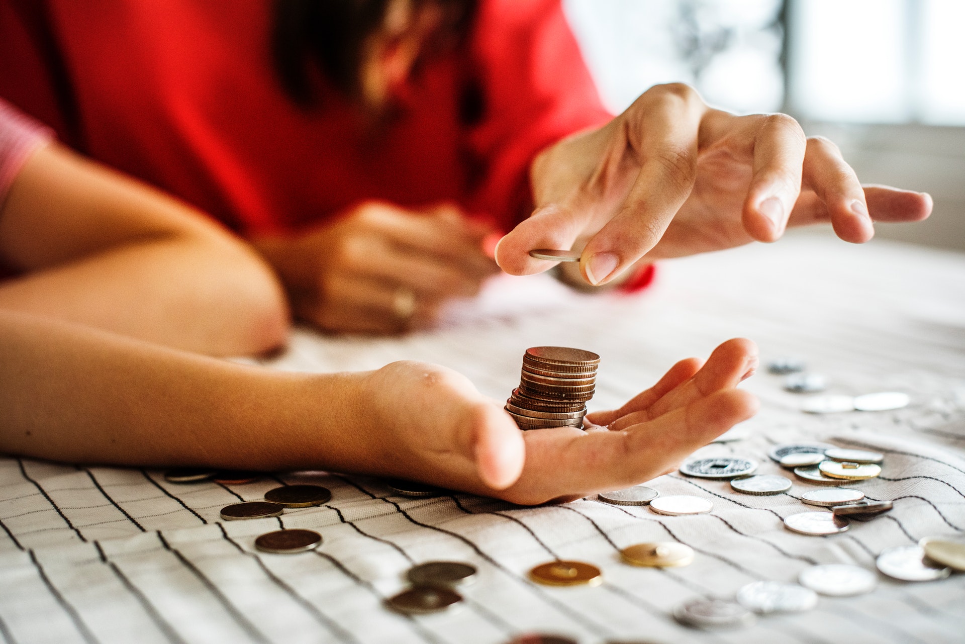 stack of change in man's hand as woman adds coins to the top of the stack