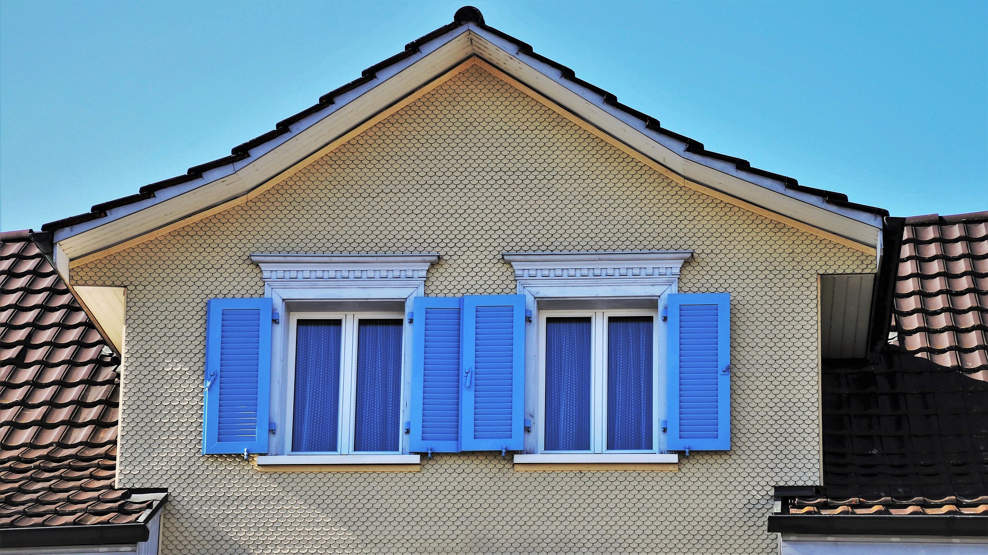 windows with blue shutters on second story of home