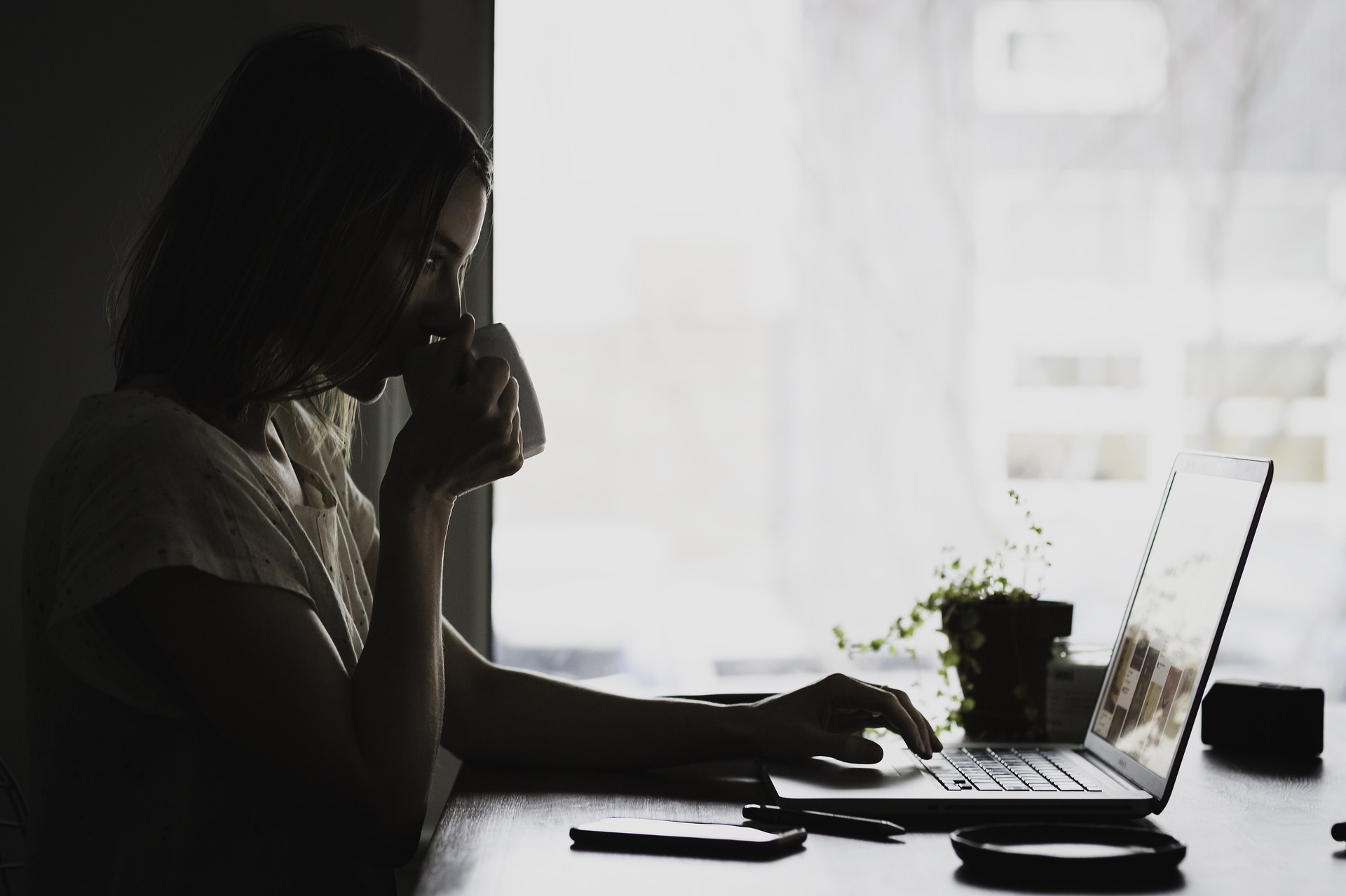 woman drinking coffee at her laptop in the morning