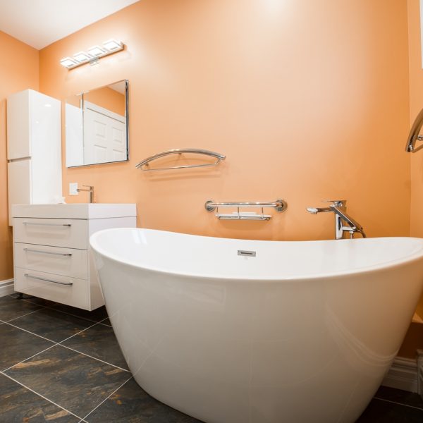 bathroom renovation with white tub and vanity and orange walls