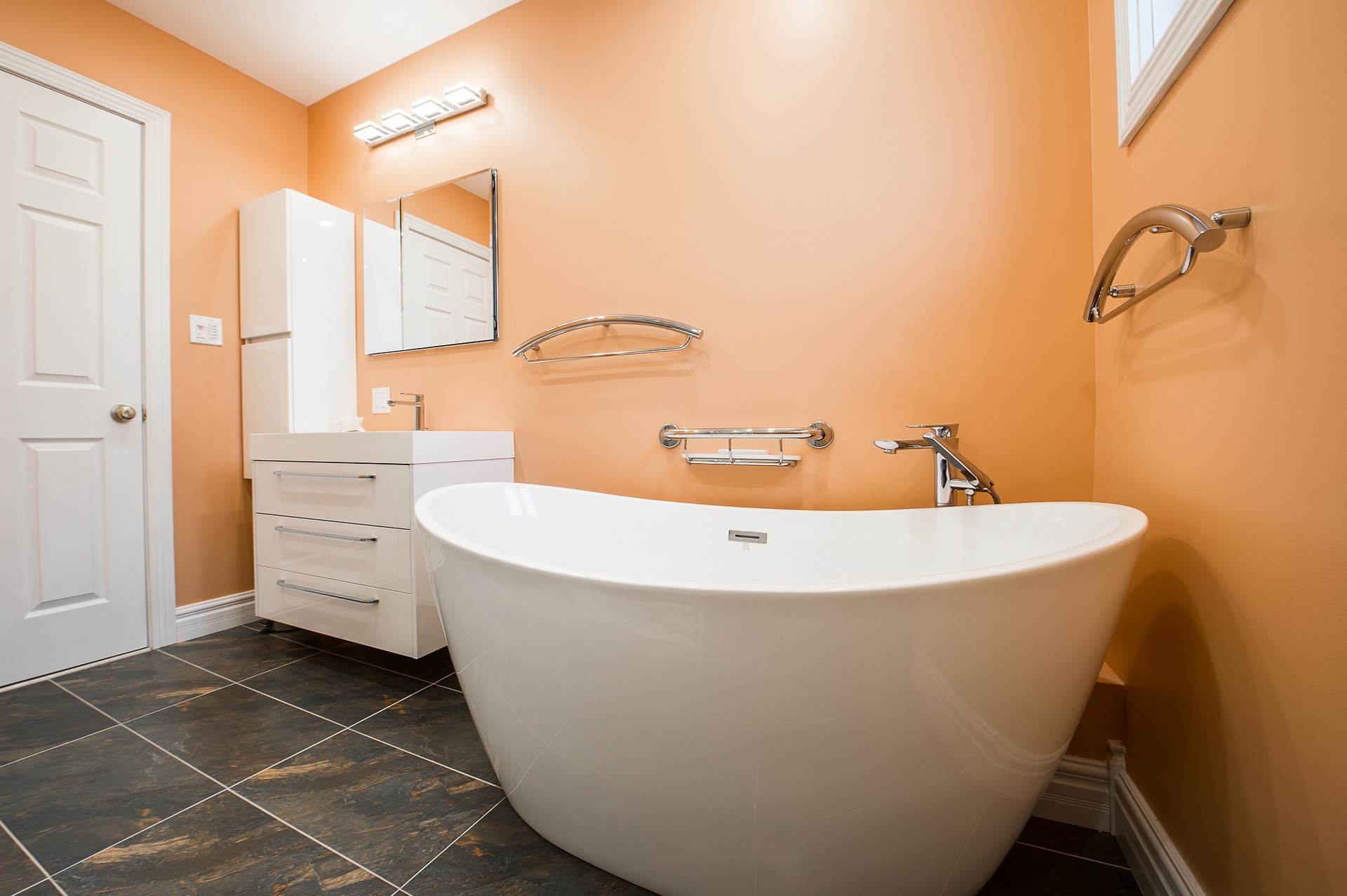 bathroom renovation with white tub and vanity and orange walls