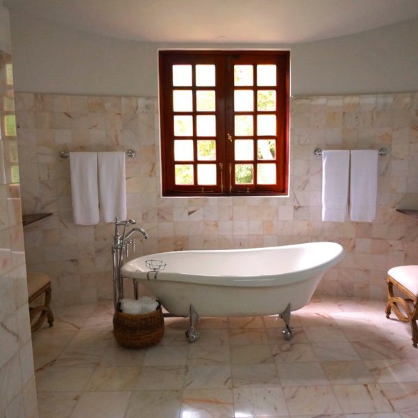 renovated home bathroom with marble tile on walls and beautiful clawfoot tub in center of room