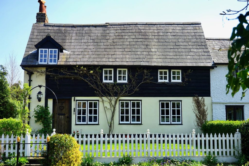 cute european-style cottage with wood shingle roof and white picket fence