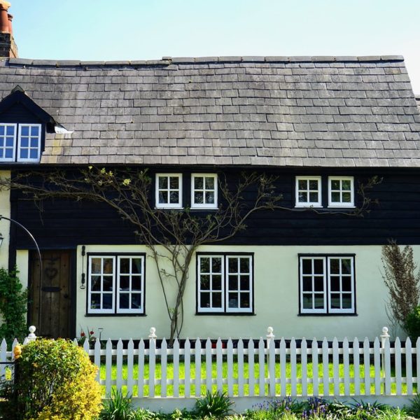 cute european-style cottage with wood shingle roof and white picket fence