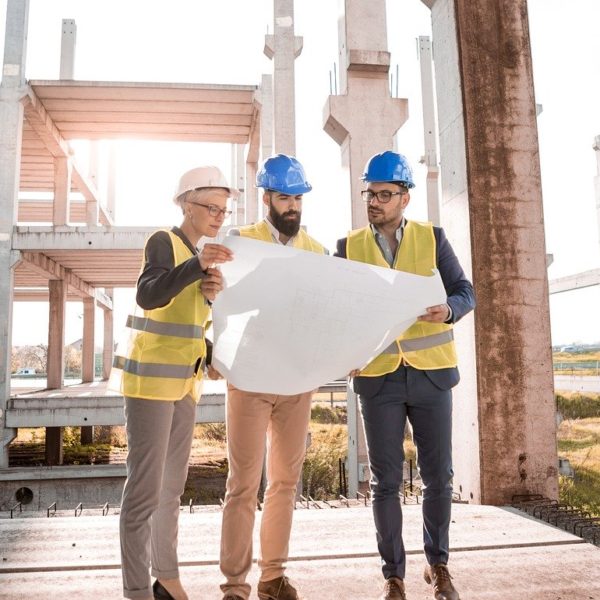 three construction planners looking at architectural plans on job site