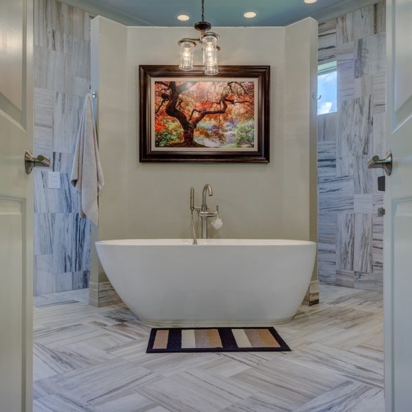 modern renovated bathroom with gray tile and soaker tub in center