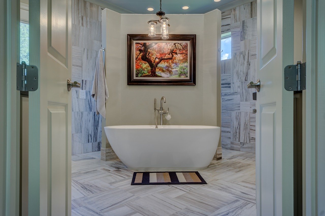 modern renovated bathroom with gray tile and soaker tub in center
