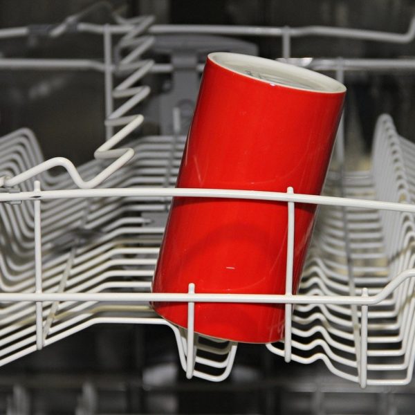 a dishwasher with white wire trays and a single red cylindrical cup
