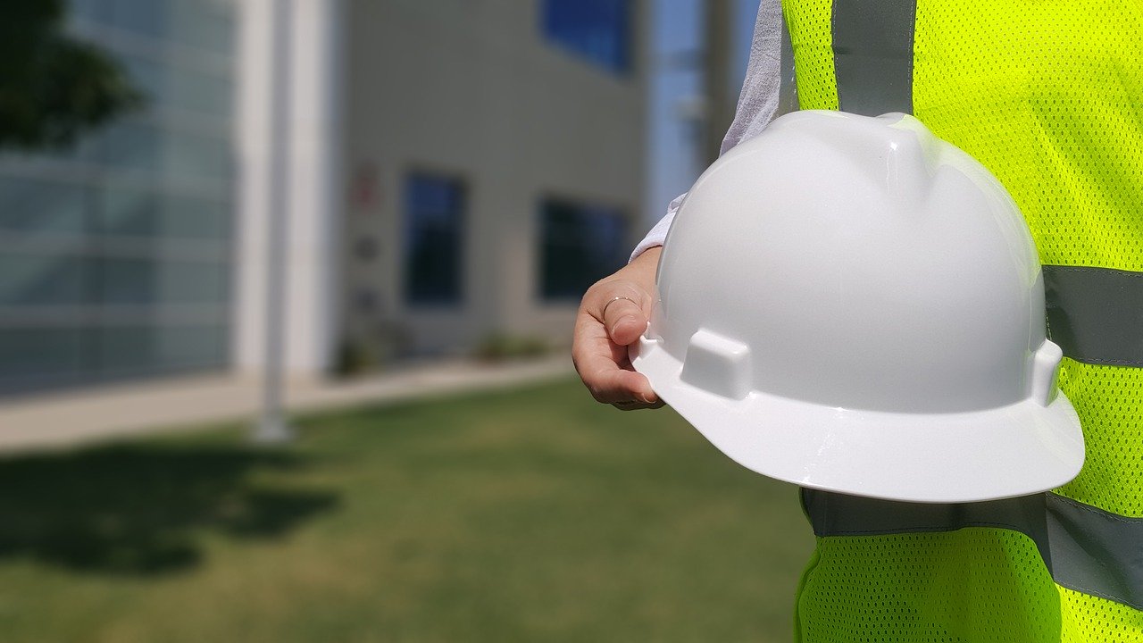 contractor in yellow safety vest holding white hard hat