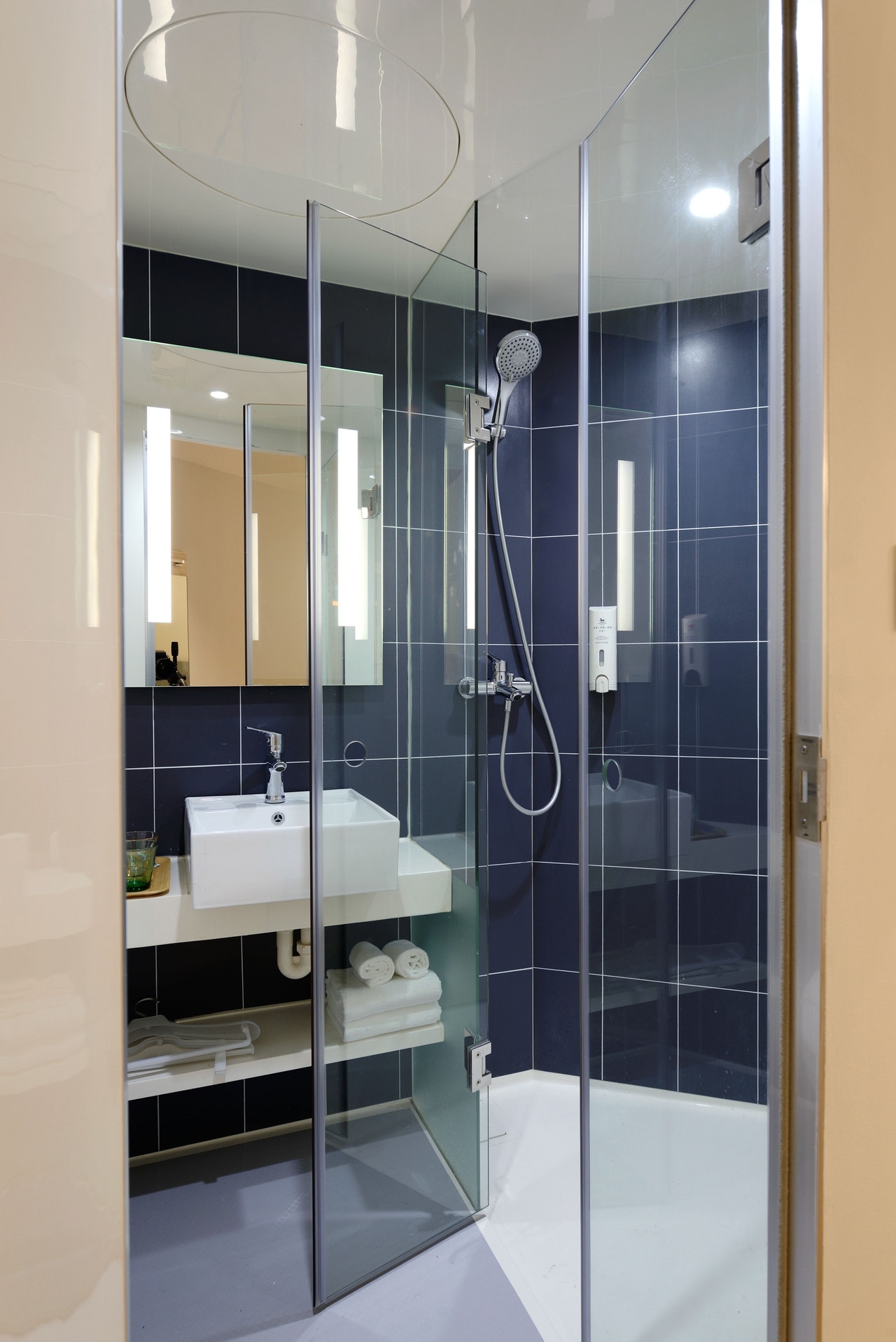 stand up shower with blue tiles and glass doorway