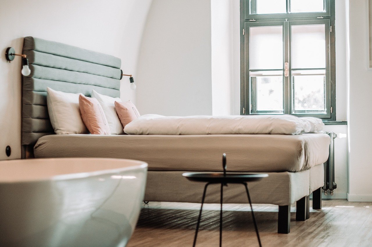 a bed with white and pink pillows and a thick comforter