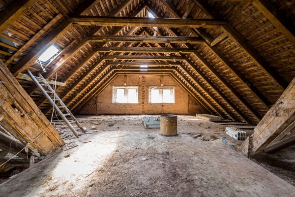 Interior of an attic with wooden beams and a ladder.