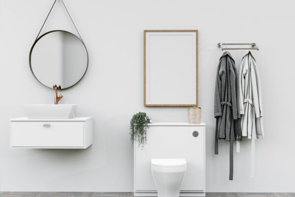 Bathroom with white toilet, sink, and mirror. Two robes (one gray and one white) hang on the wall beside the toilet and mirror.