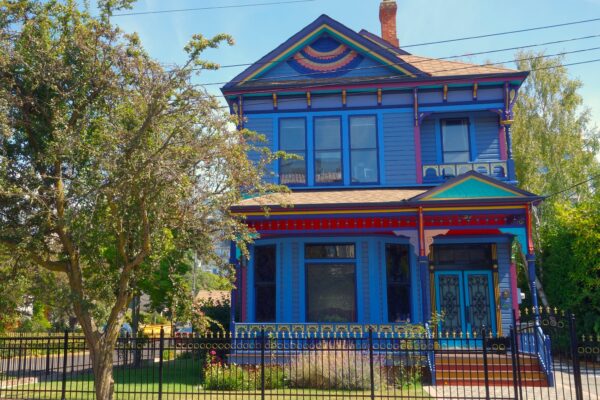 A vibrant blue house behind a black fence.